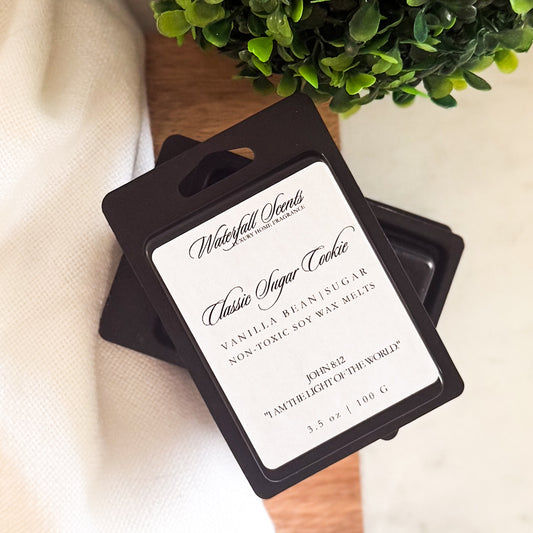Classic Sugar Cookie wax melts in a black clamshell container. Clean burning and hand poured with the cozy scent of vanilla, sweet sugar, and warm cookie dough.