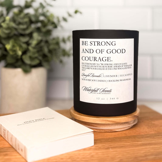 Black glass candle with wooden wick and "Be Strong and Courageous" Bible verse label. Non-toxic, hand poured for prayer and peace.