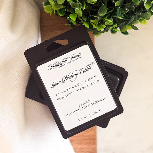 Lemon Blueberry Cobbler wax melts in a sleek black clamshell. Hand poured and clean burning with notes of lemon zest, sweet blueberries, and baked sugar.