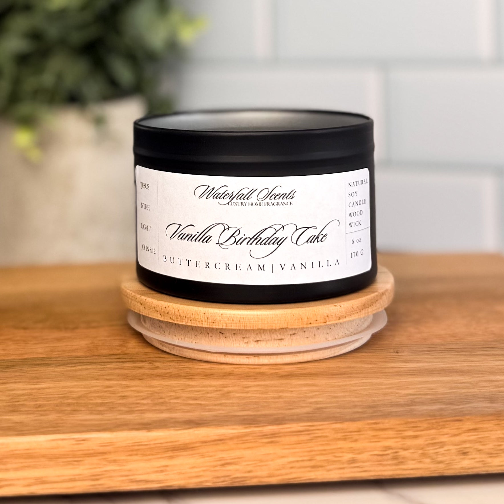 Vanilla Birthday Cake candle in a black travel tin with a white label. A cozy, natural wooden wick candle perfect for gifting and celebrating sweet moments.