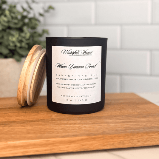 Warm Banana Bread wooden wick candle in a black glass jar with a white label. Hand poured with non-toxic ingredients for a cozy, baked scent.