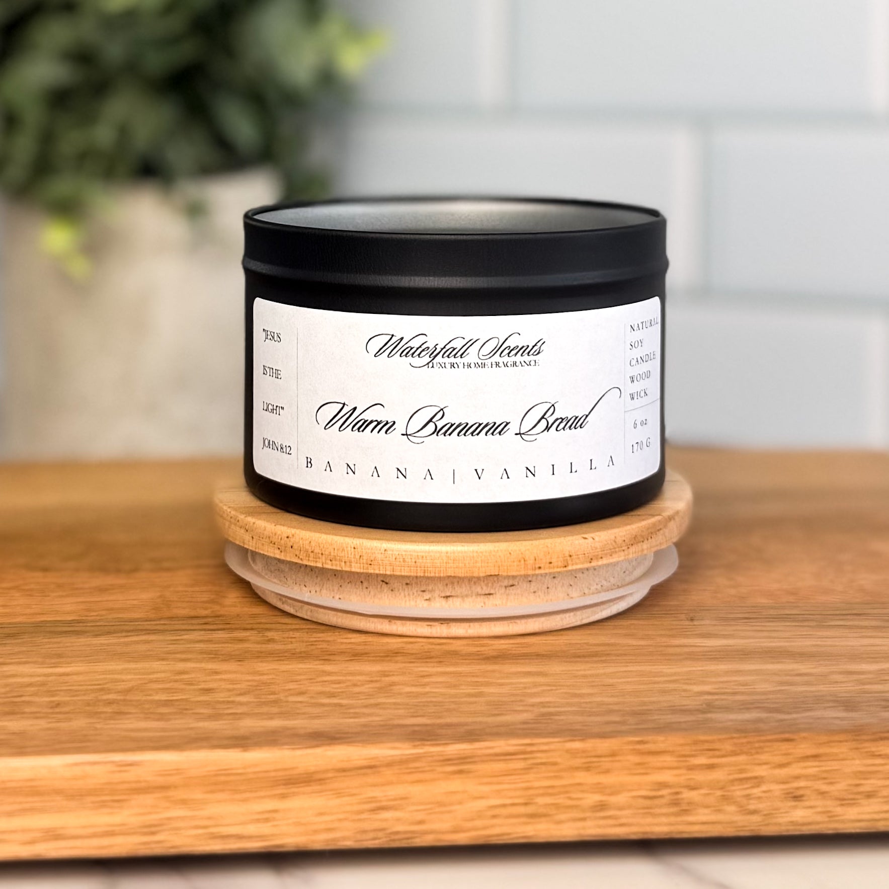 Warm Banana Bread candle in a black travel tin with a white label. A clean burning, hand poured natural candle with sweet banana and warm vanilla notes.