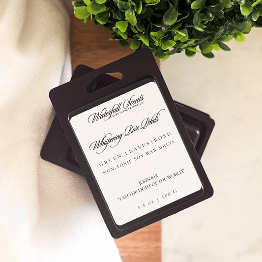 Whispering Rose Petals black clamshell natural wax melts with green leaves, rose, carnation, lily of the valley, and powder for wax melt warmers.