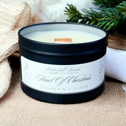 Matte black travel tin candles radiating the festive warmth of Heart Of Christmas, featuring a wooden wick for a portable and heartwarming holiday ambiance.